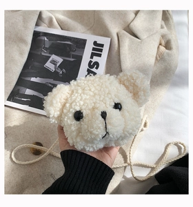 Close-up of white plush bear crossbody bag with teddy fleece texture and woven strap