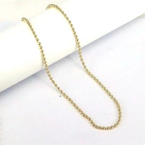 Detail of 3mm-6mm polished gold copper bead necklace chain on a minimalist white stand