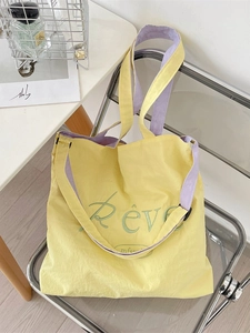 Yellow canvas tote bag with purple straps and green Rêve embroidery on an acrylic chair
