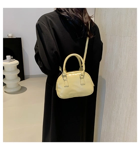 Minimalist light yellow semi-circle crossbody bag styled with a long black coat
