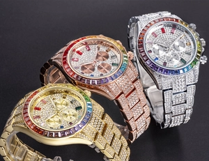 Close-up of three iced-out watches in gold, silver, and rose gold with rainbow bezels