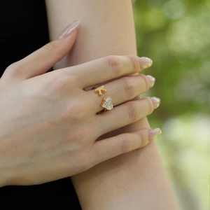 Close-up of a gold adjustable heart ring with sparkling zircons worn by a model