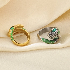 Detail of snake rings in gold and silver finish with emerald green gemstone eyes