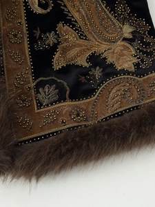 Close-up of ethnic beadwork and paisley embroidery on black velvet vest with fur trim