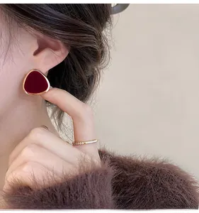 Detail view of burgundy flocked triangle earrings with gold edge on model ear