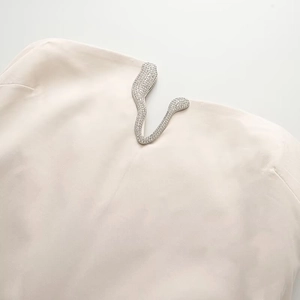 Elegant beige strapless dress featuring a V-shaped cutout with crystal metal trim