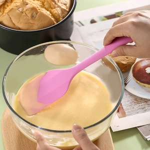 Pink large one-piece silicone spatula mixing cake batter in a bowl for baking