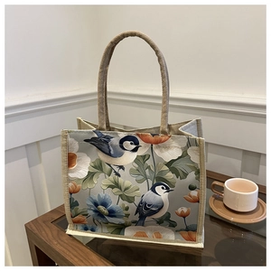Detail of linen tote bag featuring elegant blue birds and floral print on a table