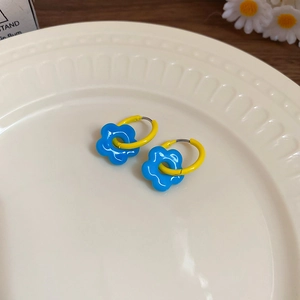 Detailed close-up of colorful flower hoop earrings with yellow ring and blue floral charms
