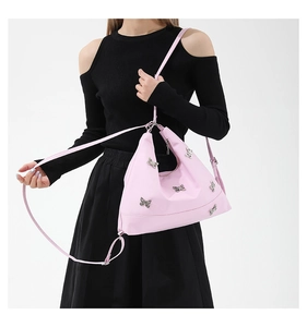 Chic pink shoulder bag featured with metallic butterfly accents on a professional model