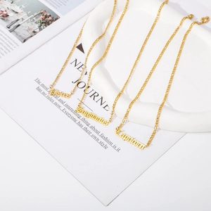 Detailed view of 18K gold plated Figaro chains with Gothic zodiac name pendants