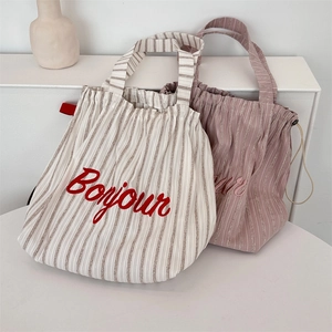 Close-up of striped canvas tote bags with Bonjour embroidery and drawstring closure