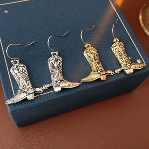 Vue détaillée de boucles d'oreilles bottes de cowboy vintage en or et argent avec gravures