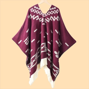 Close-up of burgundy knit poncho with beige geometric patterns and fringe detail