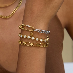 Close-up of layered two-tone paperclip bracelets with heart pendant on a woman's wrist