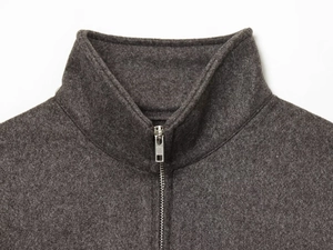 Macro detail of dark grey bomber jacket showing collar texture and silver metal zipper