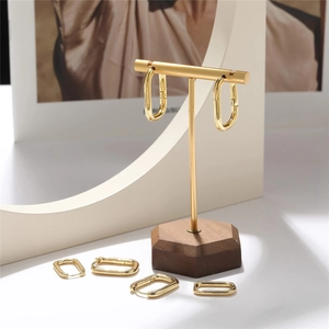 Detailed view of polished gold rectangular hoop earrings on a display stand with shadow