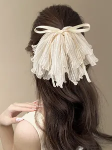Macro detail of cream bow hair claw with pleated chiffon and small pearl accents