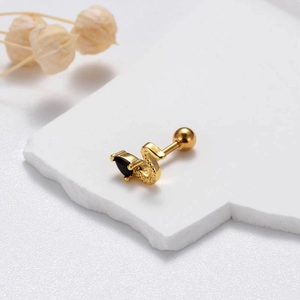 Close-up of golden snake stud earring with black drop gemstone on white background