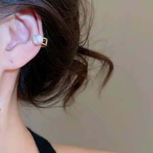 Detailed view of irregular pearl ear cuff with double golden bands on female model
