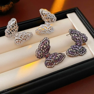 Detailed close-up of butterfly stud earrings with fine zircon stones in a jewelry box