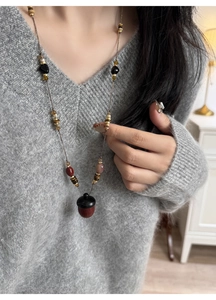 Close-up of a vintage acorn pendant necklace with mixed wood and stone beads on a grey sweater