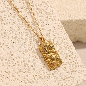 Macro shot of 18K gold plated square pendant with celestial stars, moon, and evil eye detail