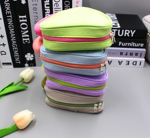 Nylon triangular makeup bags in candy colors with contrast zippers stacked on a surface