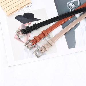 Black, brown and beige women's belts with silver buckles on white background with magazine