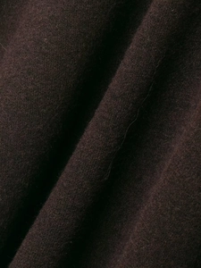 Detailed macro view of high-quality dark brown wool fabric texture with soft tassels