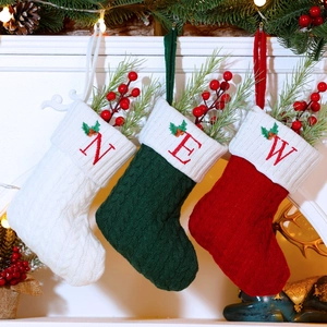 Detail of knitted Christmas stockings with letter embroidery hanging by a fireplace