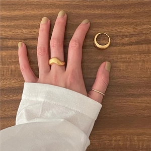 Detailed close-up of golden wavy and twisted rope rings on a wooden surface
