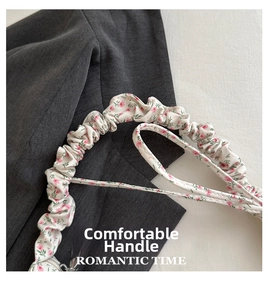 Détail de la bandoulière plissée avec motif floral romantique sur un sac en tissu Oxford