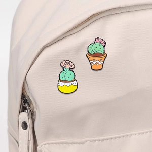 Cute cactus enamel pin badges with funny peach-shaped succulents on a fabric backpack