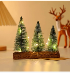 Close-up of three mini tabletop Christmas trees with warm LED lights on a wood base