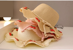 Detail of straw sun hats for girls featuring cherry embroidery and scalloped edges