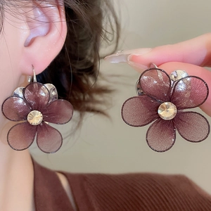 Detail of mesh flower earrings with rhinestones showing close-up texture and wear effect