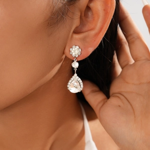 Close-up of elegant silver teardrop earrings with crystals worn by a female model