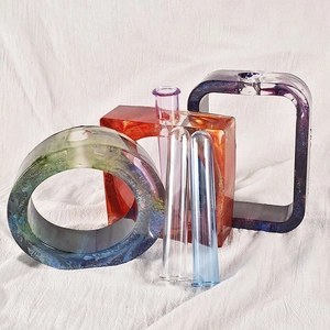 Vases géométriques artistiques en résine avec tubes en verre sur fond de tissu clair