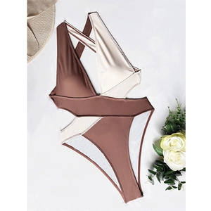 Detailed flat lay of a two-tone cross neck swimsuit with elegant beach accessories