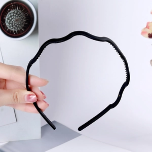 Detail view of wave shaped black plastic headband with non-slip teeth for secure styling