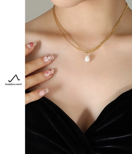 Close-up of golden stainless steel double chain necklace with a freshwater pearl charm