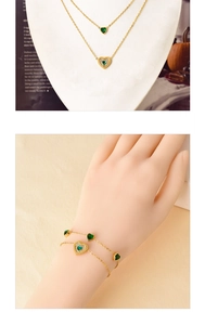 Detail of gold double-layer necklace and bracelet set with green heart-shaped gemstones