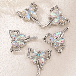 Macro detail of five silver bow pendants with sparkling rhinestones and aurora finish