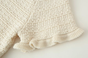 Gros plan sur la texture en tricot crème avec d'élégants détails de bords à volants