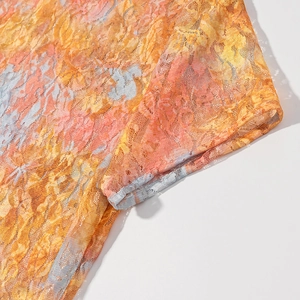 Macro detail of sheer orange lace fabric featuring intricate floral prints and fine mesh texture