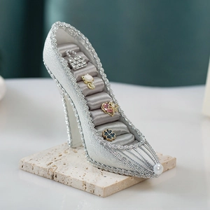 Detail of silver glitter high-heel jewelry organizer with satin ring slots and rings