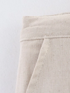 Close-up of oatmeal linen fabric texture and stitching on the waistband of shorts