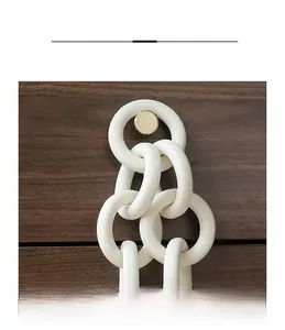 Close-up of minimalist white ceramic decorative chain rings hanging on dark wood