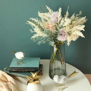 Detailed view of white and purple faux pampas grass with eucalyptus in a glass vase